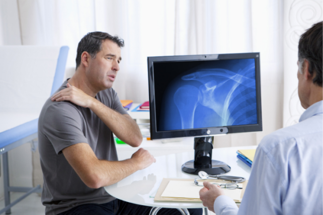 Treatments for Shoulder Arthritis Man holding shoulder with scan image on orthopaedic surgeon screen