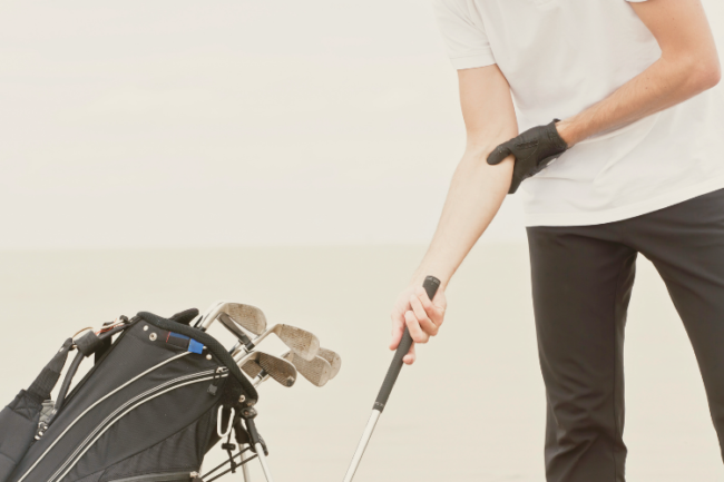 Golfers Elbow Symptoms Golf player holding elbow in pain