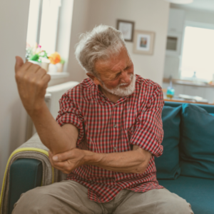 Older man holding elbow in pain in his home