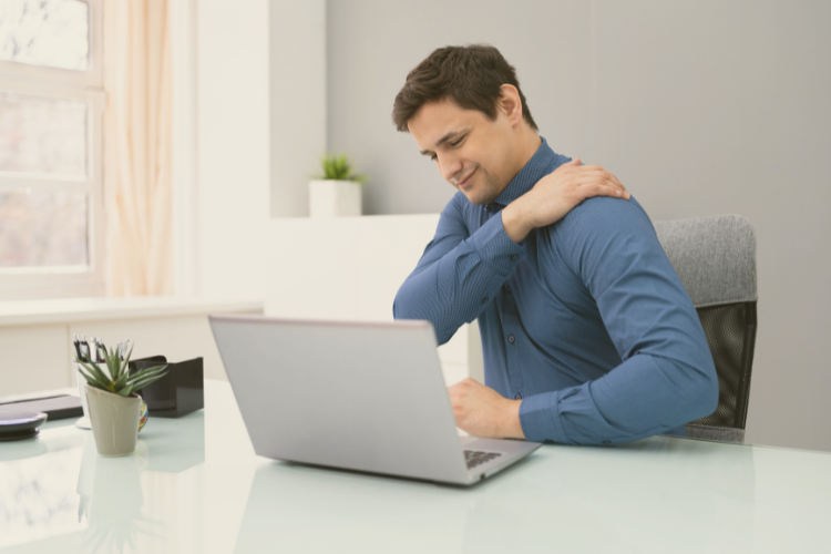 Calcific tendinitis diagnosis and treatment Middle aged man sat at a desk holding shoulder in pain