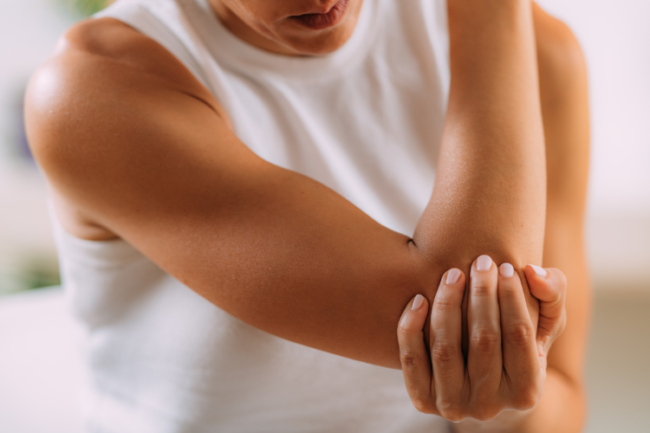 Guidelines for Tennis Elbow from BESS Woman in sports clothing holding her elbow